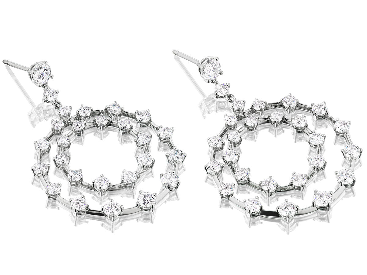 Circular platinum earrings with diamonds on a white background