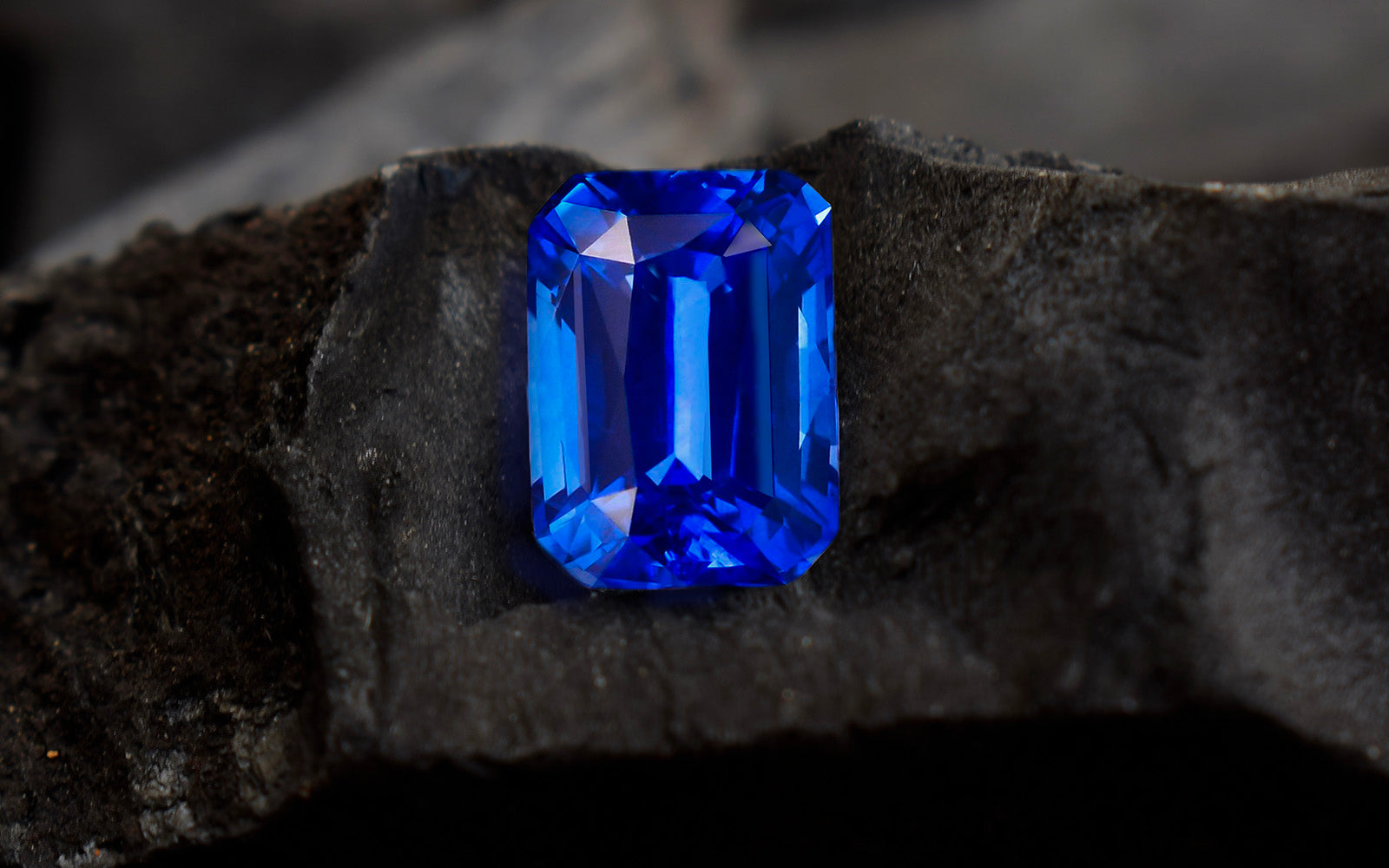 Rectangular blue gemstone on dark textured surface