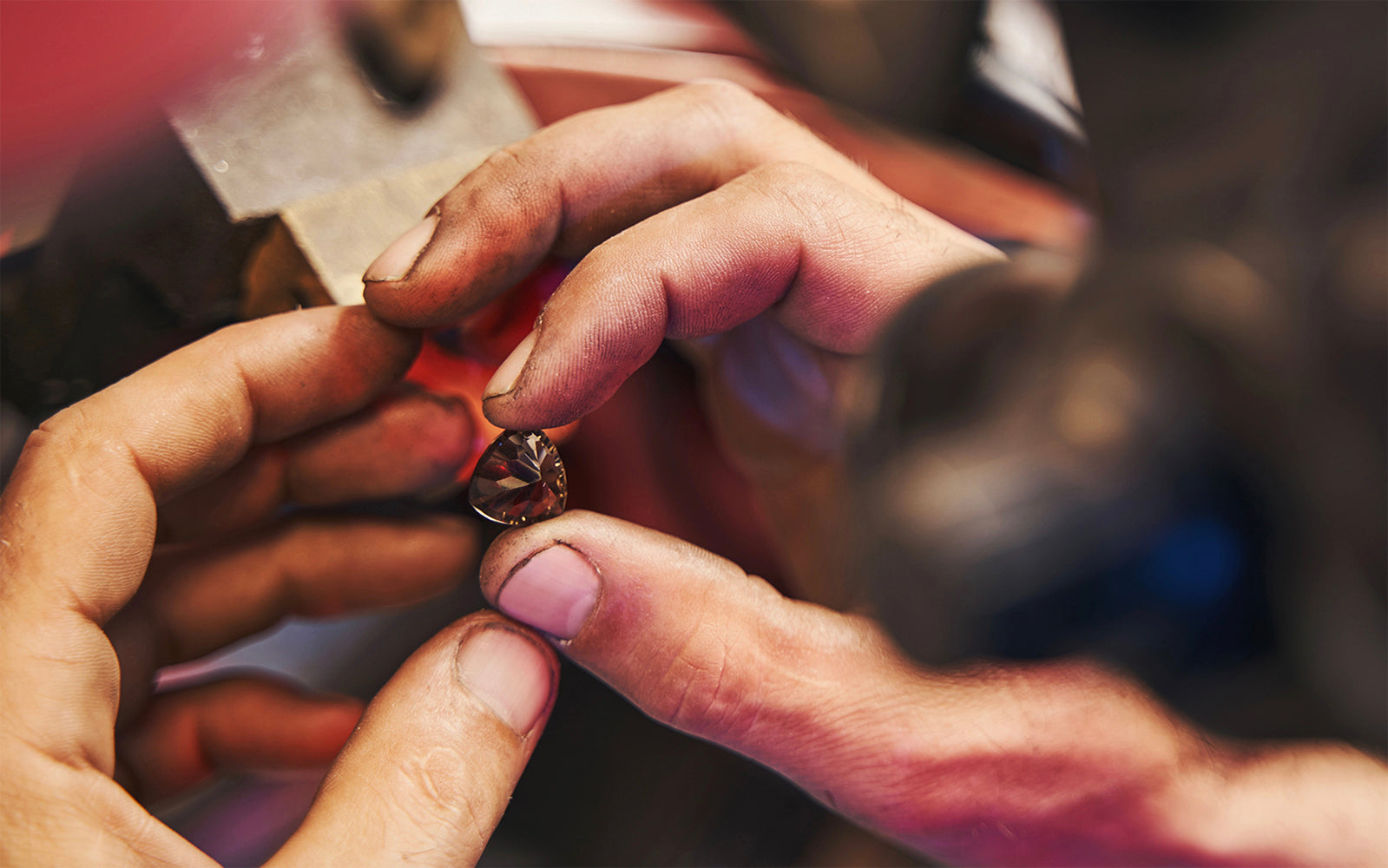 Hands of jeweler holding brownish gemstone