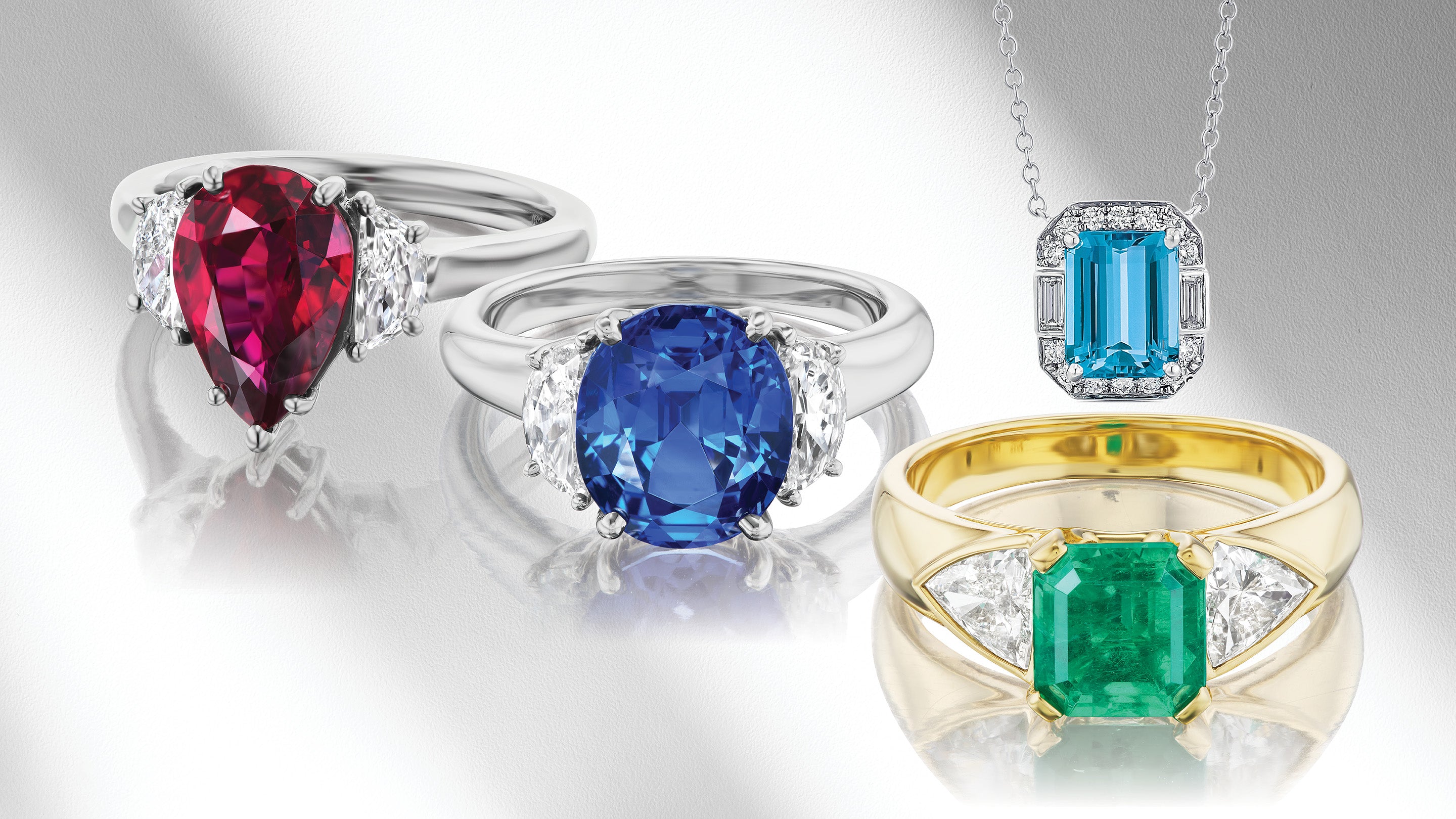 Colorful gemstone rings and pendant on gray background