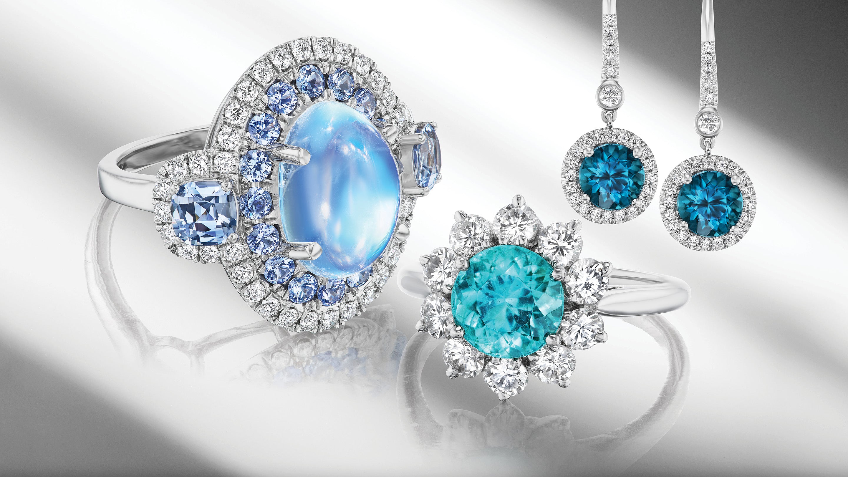 Colorful gemstone rings and earrings on gray background