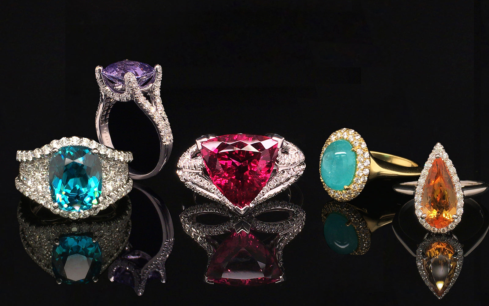 Colorful gemstone and diamond rings on black background