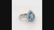 Video of rotating ring with blue gemstone and diamonds on white background