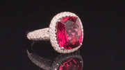 Video of rotating platinum ring with a cushion rubellite and  diamond pave on a black background.