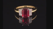 Video of rotating three-stone ruby ring with two baguette diamonds set in platinum on a yellow gold band on a black background