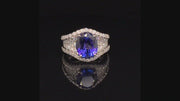 Video of rotating ring with blue gemstone and diamonds on black background