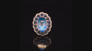 Video of rotating platinum ring with a large moonstone surrounded by cabochon sapphires and diamonds on a black background