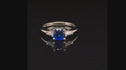 Video of rotating platinum three-stone sapphire ring with tapered baguettes on black background.