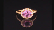 Video of rotating 20K pink gold ring with pink sapphire and diamond halo on black background