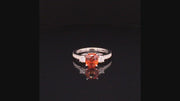 Video of rotating ring with cushion-cut orange sapphire ring with diamonds in platinum on black background