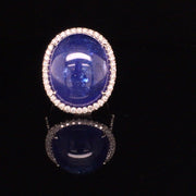 Video of rotating ring with blue gemstone and diamonds on black background
