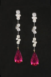 Drop earrings with diamond clusters on platinum wire and pear-shape rubellites on a black background