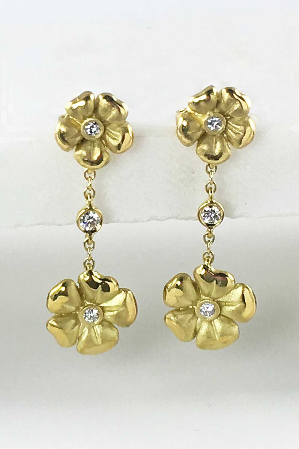 18K yellow gold and diamond drop earrings featuring a flower motif on a white background