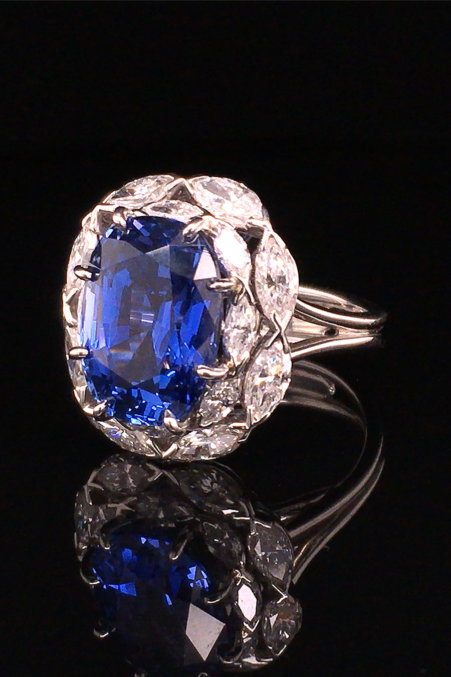Sapphire surrounded by marquise diamonds in a platinum ring on black background