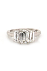 Platinum ring with three emerald-cut diamonds on white background
