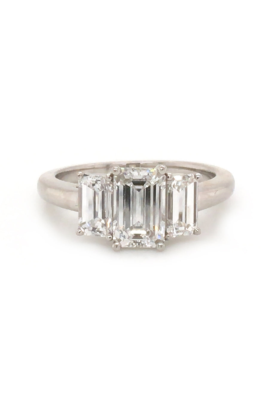 Platinum ring with three emerald-cut diamonds on white background