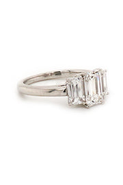 Side view of platinum ring with three emerald-cut diamonds on white background