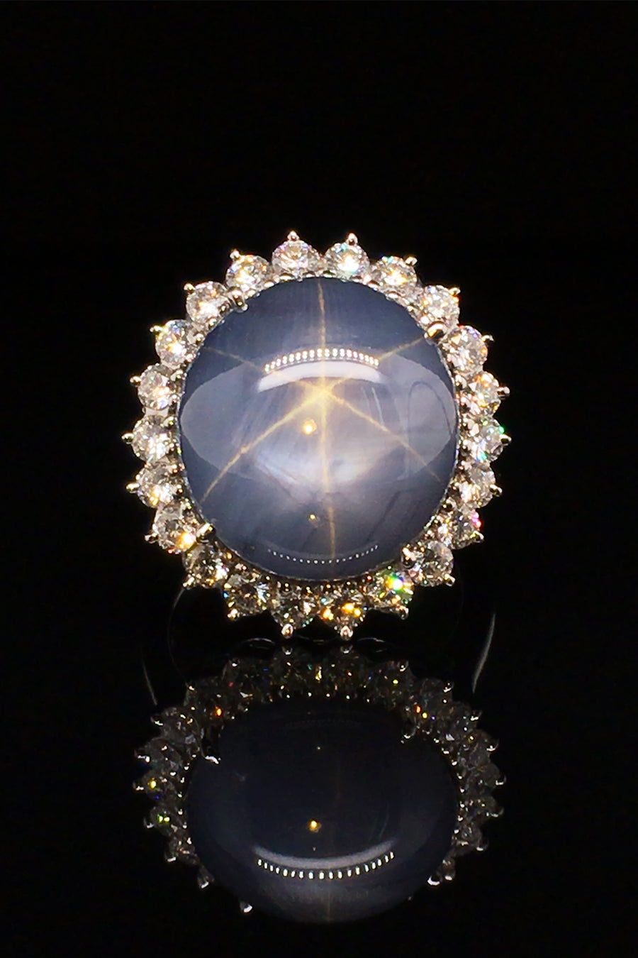 Platinum ring with large blue-gray star sapphire and brilliant diamonds on a black background.