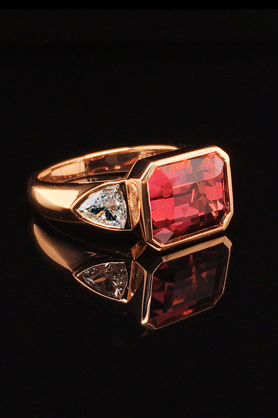 20K pink gold ring with a rubellite and diamonds on black background.