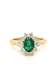 18K gold ring featuring an oval emerald with diamonds on a white background