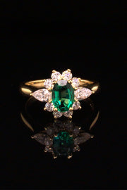 18K gold ring featuring an oval emerald with diamonds on a black background