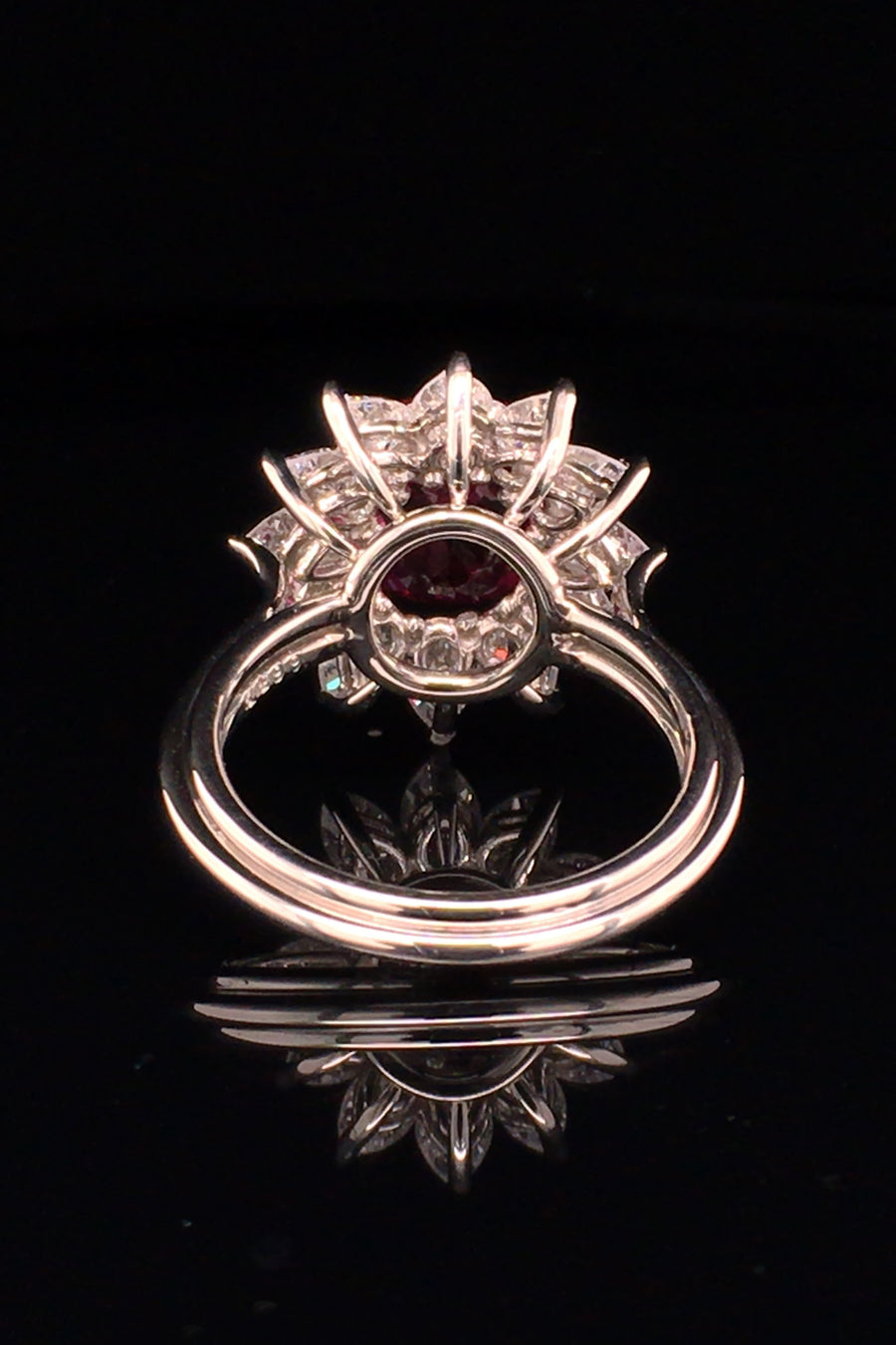 Back view of platinum ring featuring a ruby surrounded by pear shape diamonds black background.
