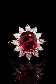 Platinum ring featuring a ruby surrounded by pear shape diamonds black background.