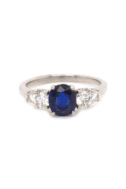 Platinum ring with an oval sapphire with four diamonds on white background