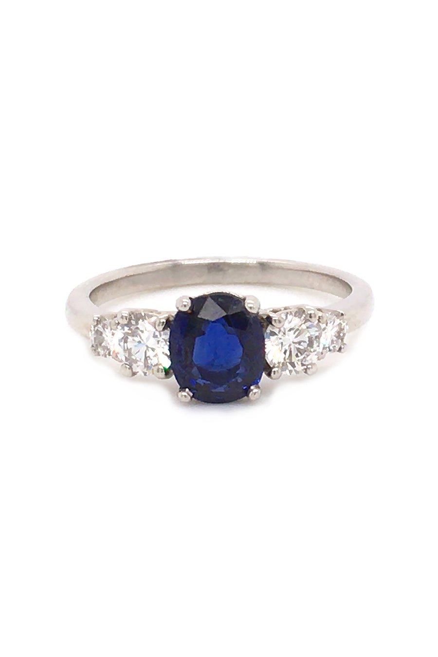 Platinum ring with an oval sapphire with four diamonds on white background