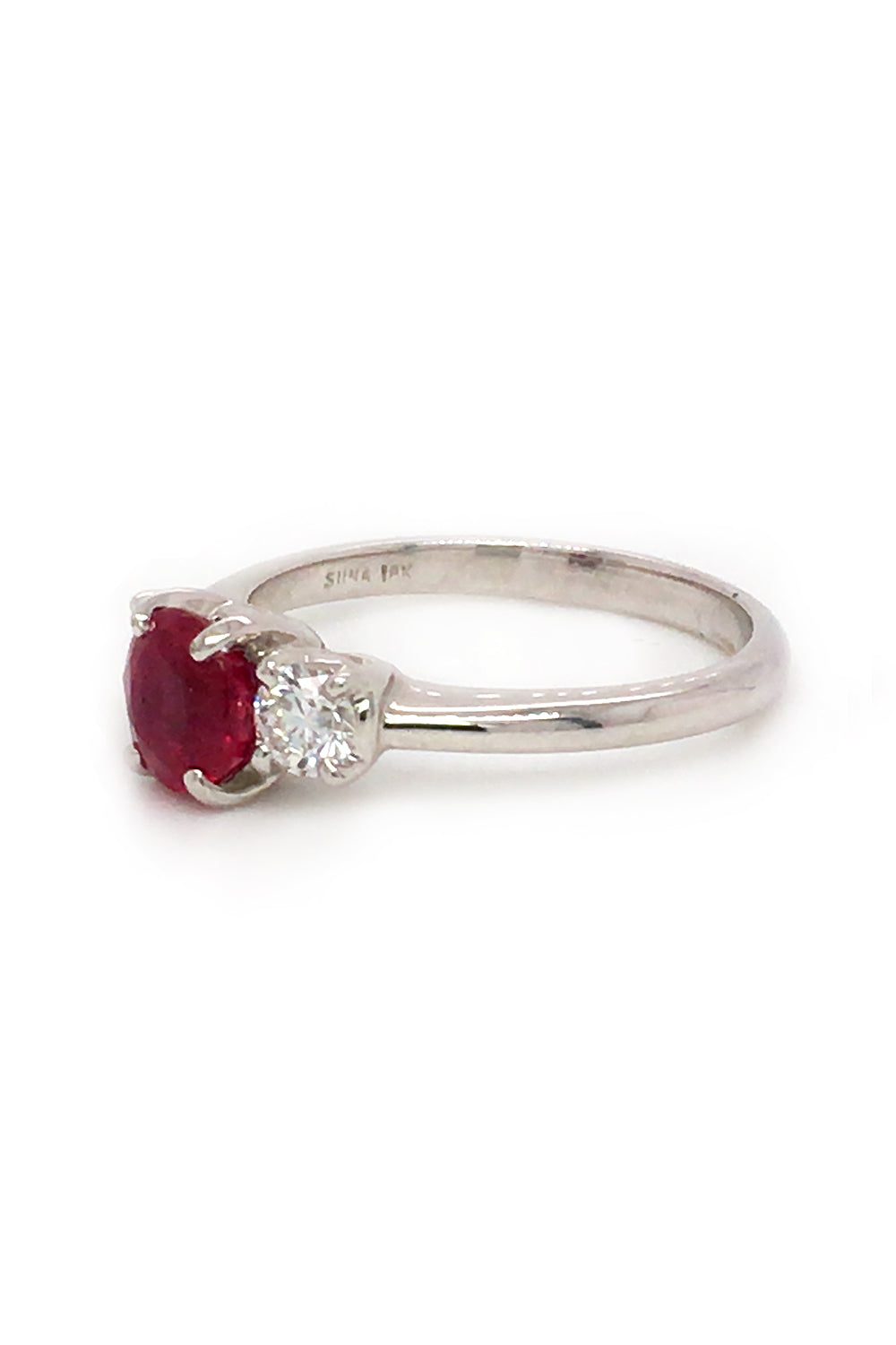 Angle view of 18K white gold ring featuring a ruby and two round diamonds on white background