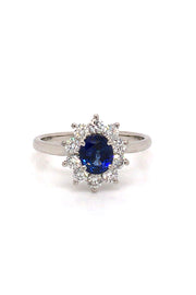 Platinum ring with oval blue sapphire surrounded by brilliant diamonds on white background.