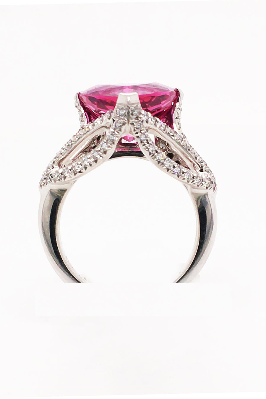 Side view of 18K white gold ring featuring a large trilliant cut rubellite with diamonds on a white background