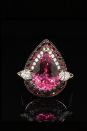 18K white gold ring with a pear-shape rubellite surrounded by diamonds and rubies with a black rhodium finish on a black background