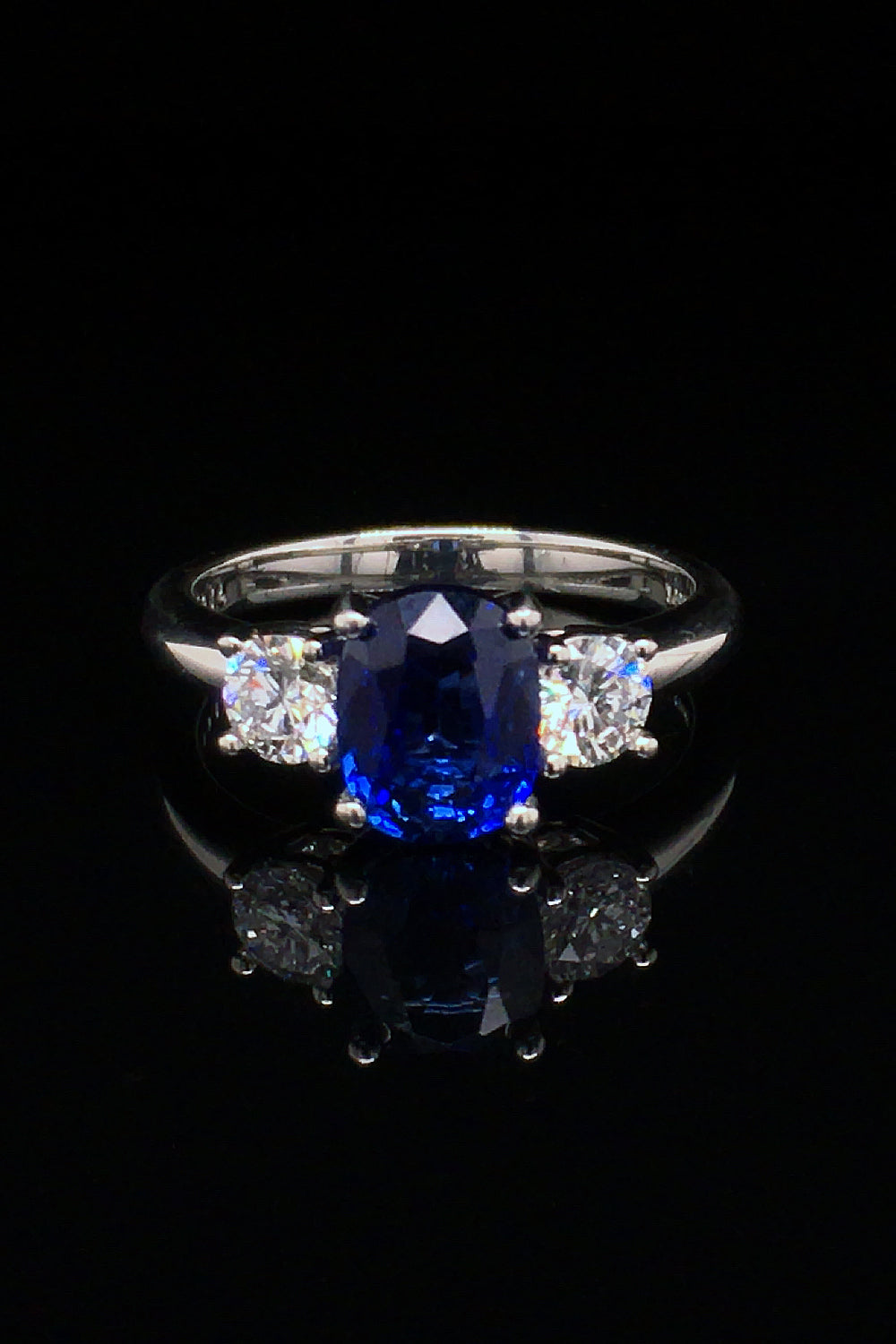 Platinum ring with oval sapphire and brilliant diamonds on a black background.