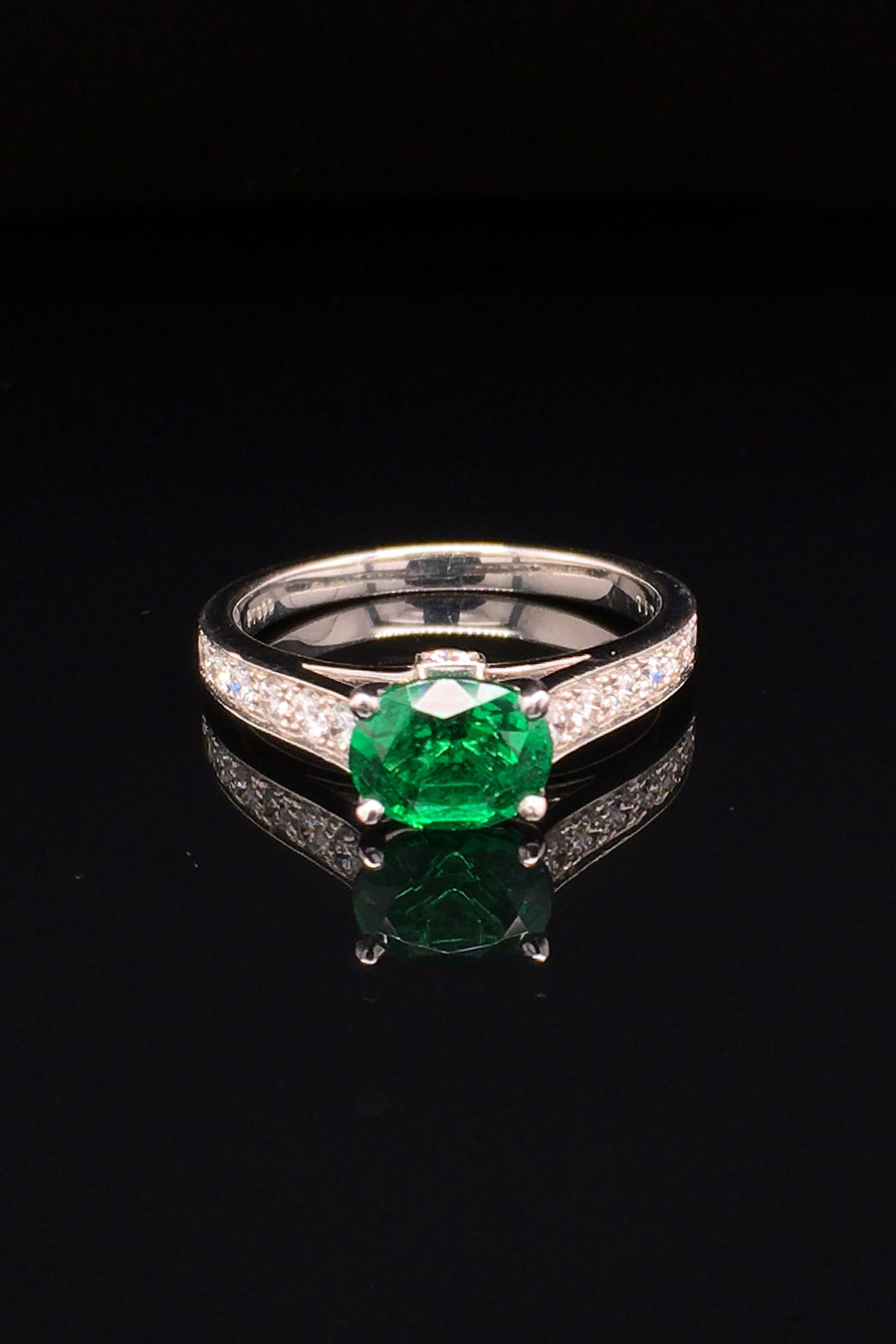 Platinum ring  with oval emerald and diamonds on black background