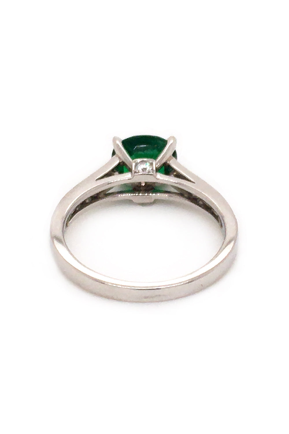 Back view of platinum ring with oval emerald and diamonds on white background