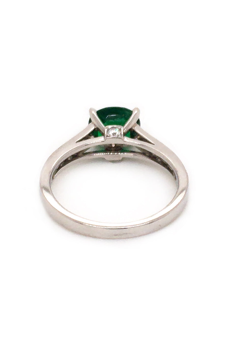 Back view of platinum ring with oval emerald and diamonds on white background