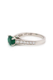Angle view of platinum ring  with oval emerald and diamonds on white background