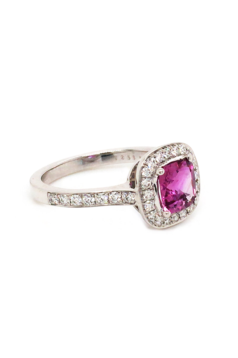Angle view of 18K white gold ring with cushion-cut pink sapphire and round diamonds on white background