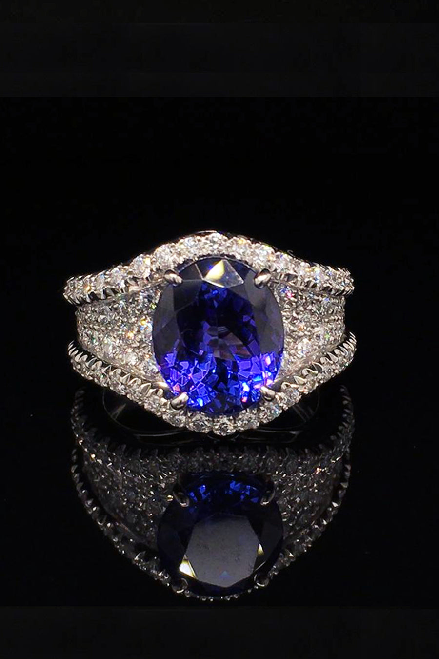 Platinum ring with an oval tanzanite and diamond pave on a black background