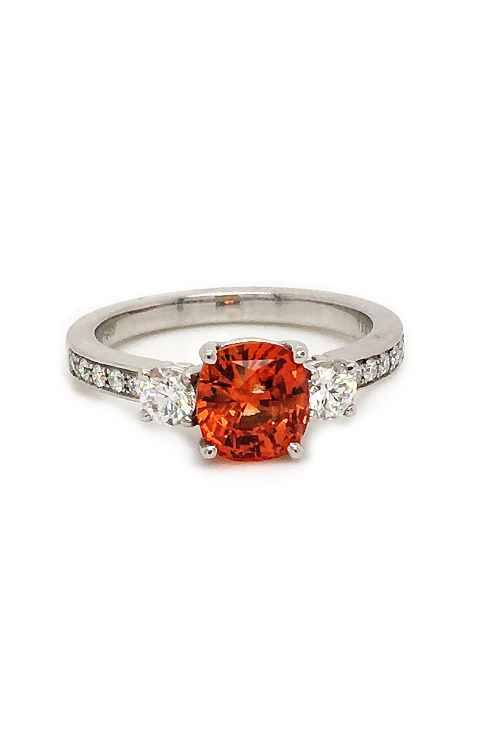 Cushion-cut orange sapphire ring with diamonds in platinum on white background