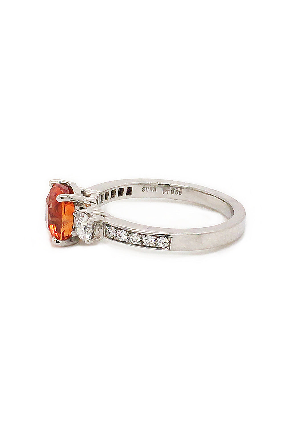 Side view of cushion-cut orange sapphire ring with diamonds in platinum on white background