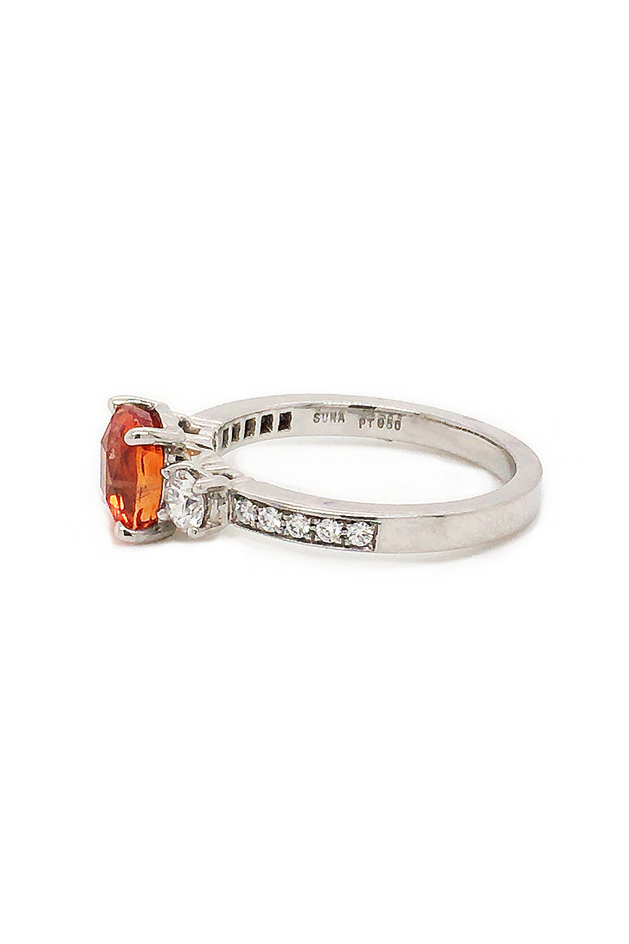 Side view of cushion-cut orange sapphire ring with diamonds in platinum on white background