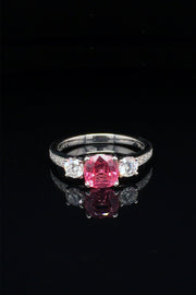 Platinum ring with pink-orange spinel and diamonds on black background