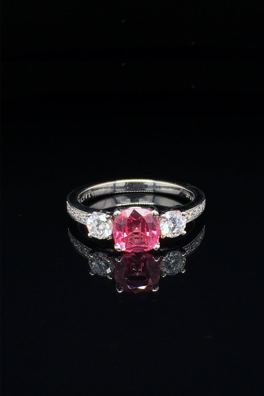 Platinum ring with pink-orange spinel and diamonds on black background
