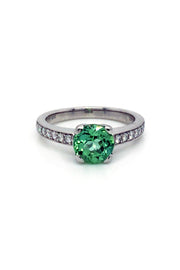 Round mint green tourmaline set in a platinum ring with diamonds on white background