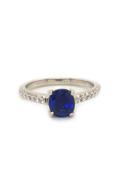 Platinum ring featuring a sapphire with round diamonds on white background