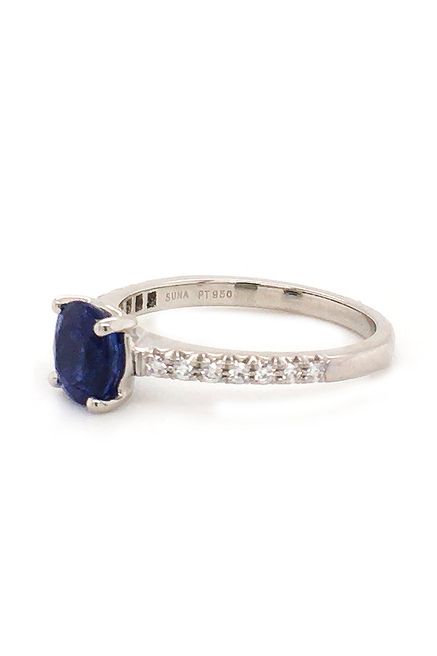 Angle view of platinum ring featuring a sapphire with round diamonds on white background