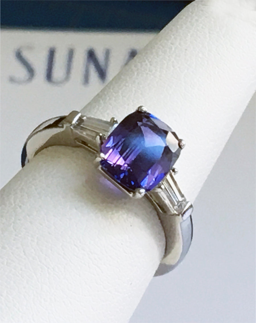 Platinum ring with purple blue color-change sapphire and tapered baguette diamonds on white ring display