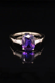 Platinum ring with purple blue color-change sapphire and tapered baguette diamonds on black background